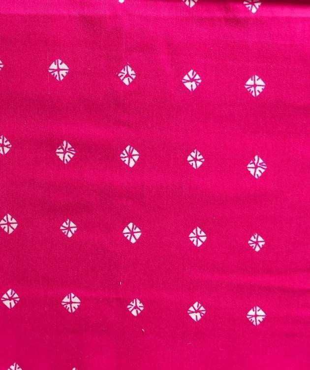 pink fabric with a repeating pattern of small white geometric or floral motifs.